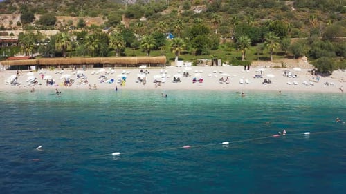 Weißer Sand Hidayet Beach und türkisfarbenes Meer, umgeben von Bergen im touristischen Kas Town, Türkei