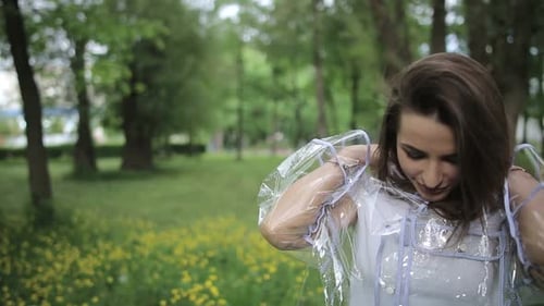 Das Mädchen lächelt und lacht im Regen. Der Regen fällt, die Tropfen fallen auf sein Gesicht