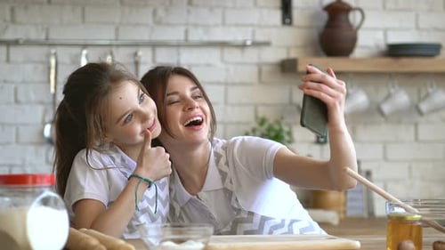 Mother and Daughter Taking Selfie in Kitchen