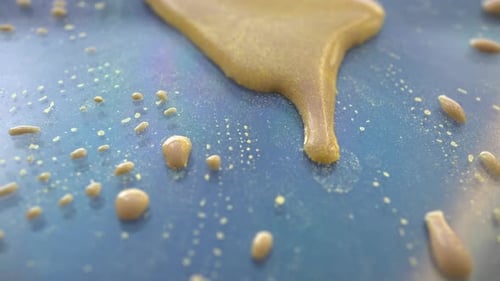Gold Liquid Dripping and Splattering on Blue Surface