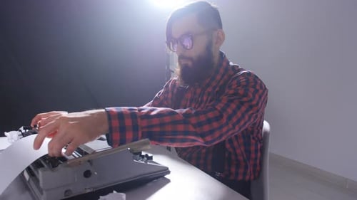 Man Typing on Vintage Manual Typewriter at Desk