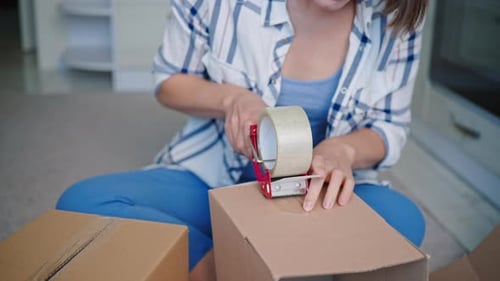 Woman sealing cardboard box with packing tape