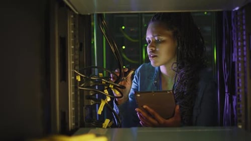 Woman Examines Server Cables with Tablet in Data Center