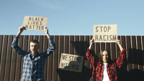 Man and Woman Holding Protest Signs in Daylight