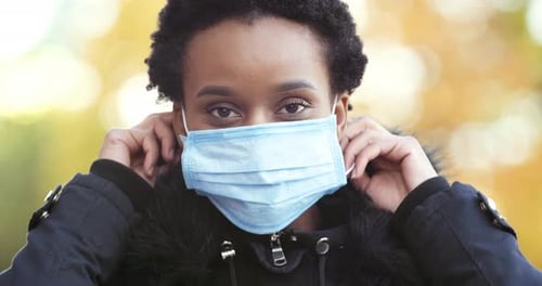 Woman Puts On Surgical Mask and Gives Thumbs Up