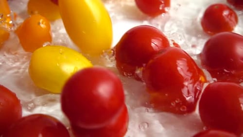 Rote und gelbe Kirschtomaten ins Wasser fallen lassen.