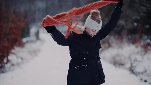 Woman Puts on Scarf in Snowy Winter Forest