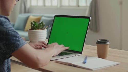 Homme tapant sur le clavier d'un ordinateur portable avec écran vert à la maison