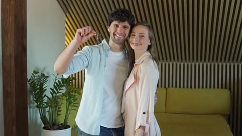 Happy Couple Hold Keys in Modern Apartment