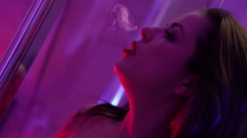 Woman with Dark Hair Vaping Under Purple Light
