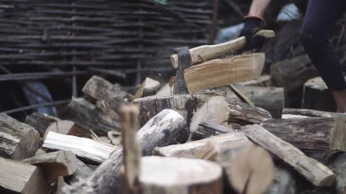 Axe Cutting Logs Into Firewood Pile