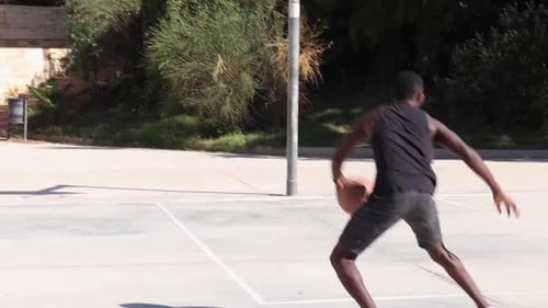 Black man playing basketball on sports ground