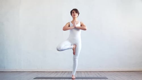 Junge und fitte Frau, die in der Klasse Indoor Yoga praktiziert.