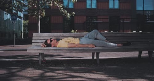 Man lays on park bench during sunny day