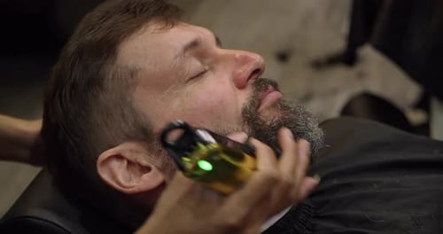 Barber Trimming Man's Beard with Electric Trimmer