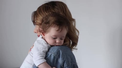 mother holding a newborn baby on her shoulder at home
