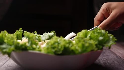 Hand Serving Fresh Green Salad with Spoon