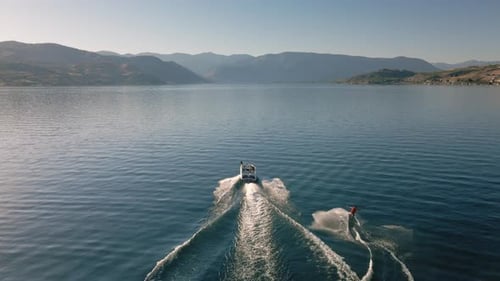 Drone Following Boat Towing Wakeboarder On Scenic Lake Chelan With Desert Mountains