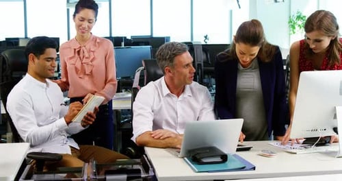 Executives interacting with each other at desk in office