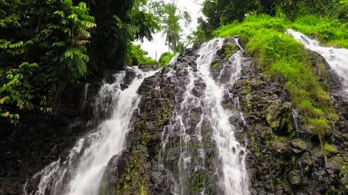 Tropical Waterfall Flowing Down Rocky Mountainside
