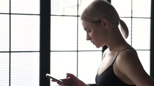 Woman Uses Mobile Phone in Urban Gym