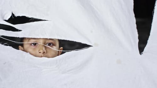Garçon réfugié regardant à travers le tissu déchiré