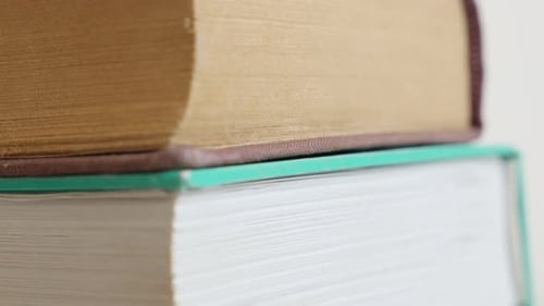 Tilting on pile of books darkened with shelf dust 4K 2160p 30fps UltraHD footage - Slow tilt on st