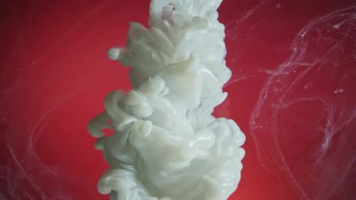 White nacreous paint in water against red background
