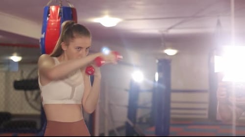 Young Woman Boxing with Dumbbells in Gym