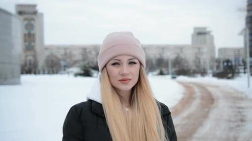 Blonde Woman Standing in a Snowy City in Winter