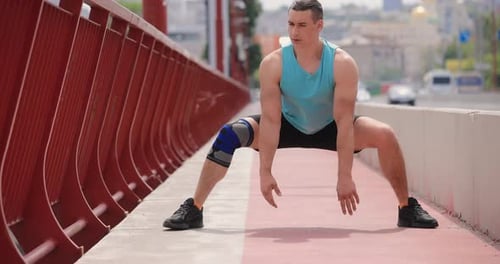 Man Stretches Leg Before Running on a Bridge