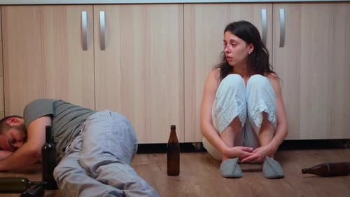 Injured Woman Talking on Phone Near Sleeping Man