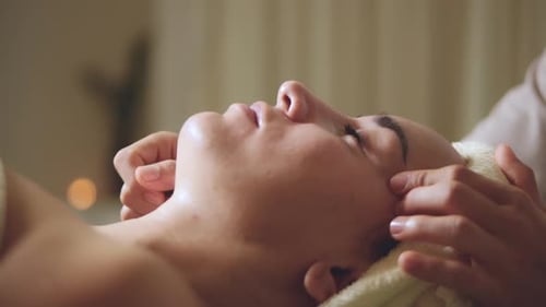 Relaxed Woman Lying on Spa Bed for Facial and Head Massage Spa Treatment By Massage Therapist in a