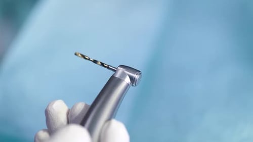Nahaufnahme der Little Bor-Maschine in der Hand des Zahnarztes in der Zahnarztpraxis, Vorbereitung auf die Behandlung