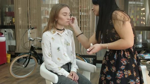 Makeup Artist Applying Eye Shadow to a Young Woman