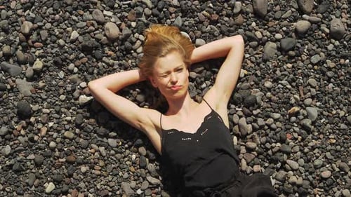 Woman Relaxes on Rocky Beach From Above