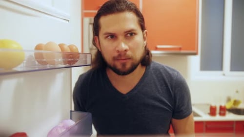 Man Opens Refrigerator Door in his Kitchen