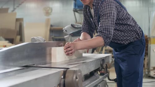 Man Smoothing Wood Block with Machine in Workshop