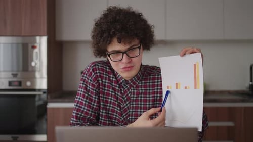 Young Adult Presenting Financial Data from Home