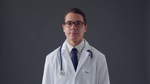 Studio portrait of young professional medical doctor standing over grey background