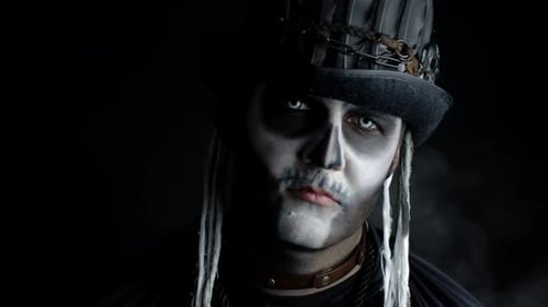 Sinister Man with Horrible Halloween Skeleton Makeup Appearing From Darkness When Light Falls on Him