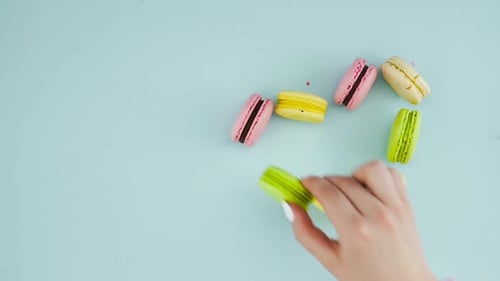 Macarons ou macarons posés en forme de cœur sur une surface bleu pastel. Gros plan.