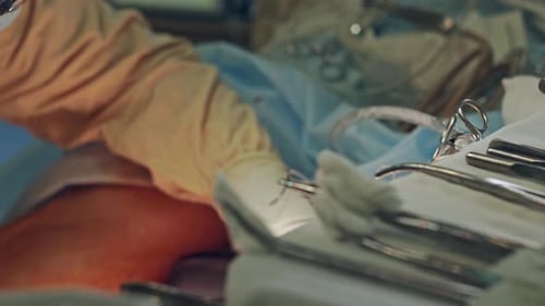 Medical Instruments on a Tray During Surgery with an Aspirating Tube Linked To a Patient Zoom