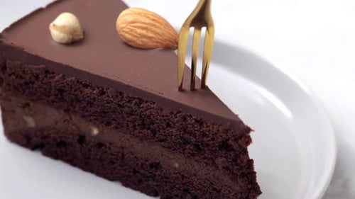 Fork Takes Piece of Chocolate Cake with Nuts