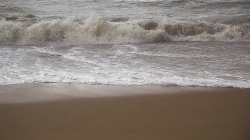 a Storm Wave Rolls Over a Sandy Beach