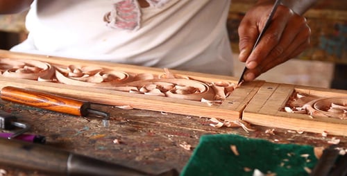Craftsman Carefully Carving Ornate Wood Design with Precision