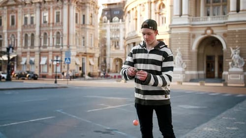 Young Boy Playing with Kendama Outdoors in City Center During Sunset