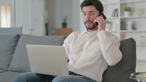 Man Working From Home on Laptop and Talking
