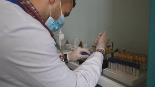 Medical Professional Filling Vials in Laboratory Setting