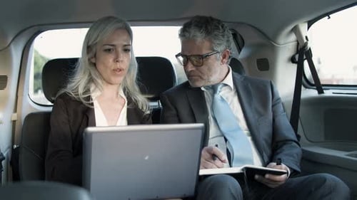 Homme prenant des notes dans un carnet et femme tenant un ordinateur portable sur les genoux
